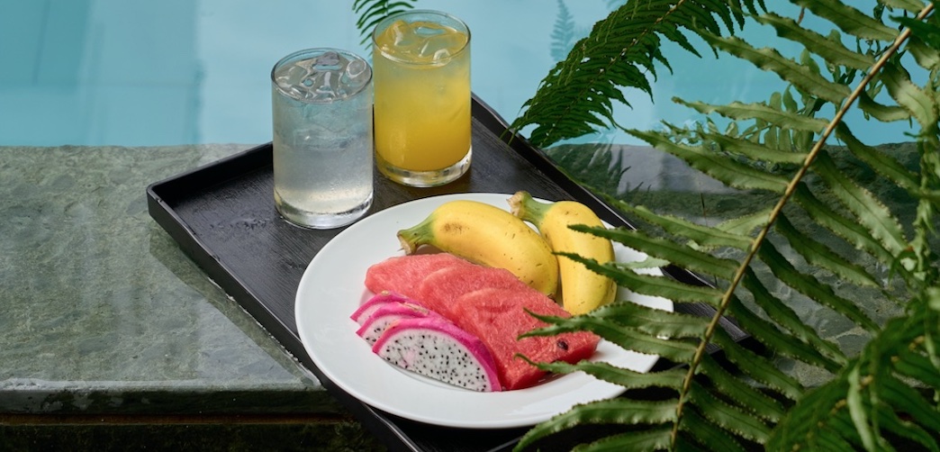 A tray of drinks and fresh fruit on the edge of the courtyard pool