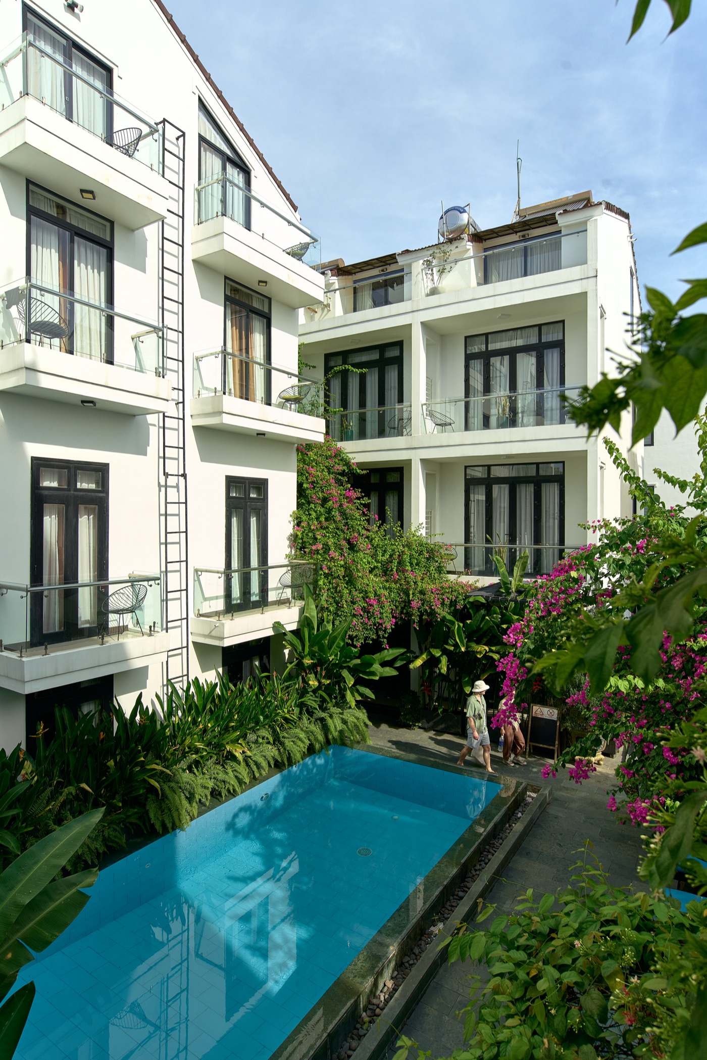 Guests walking past the pool between the hotel's buildings